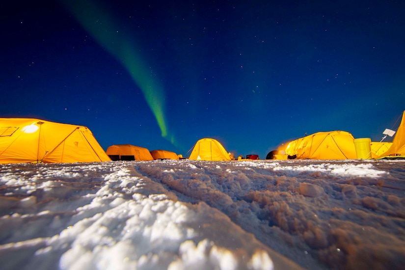 The northern lights flare over tents.