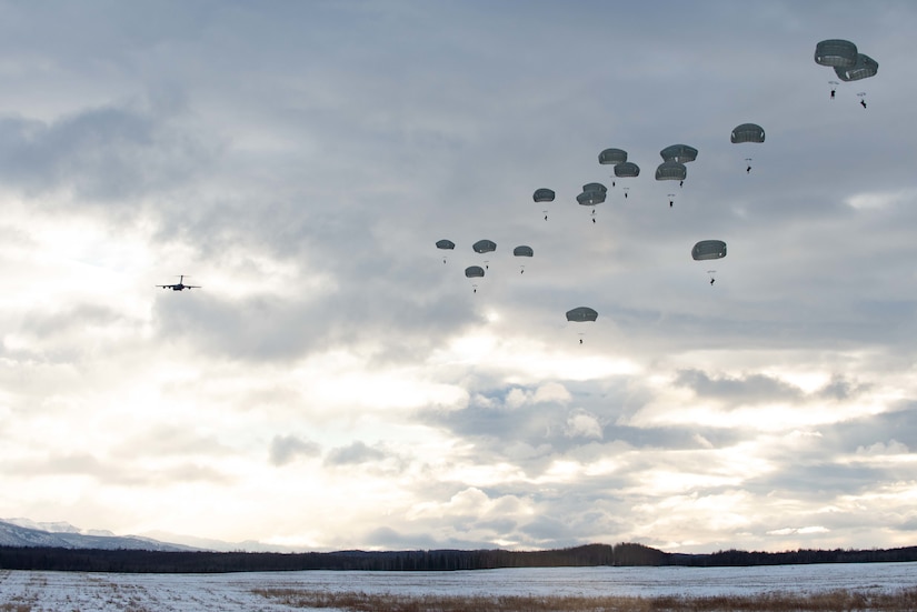 Paratroopers drop onto a snow-covered field.