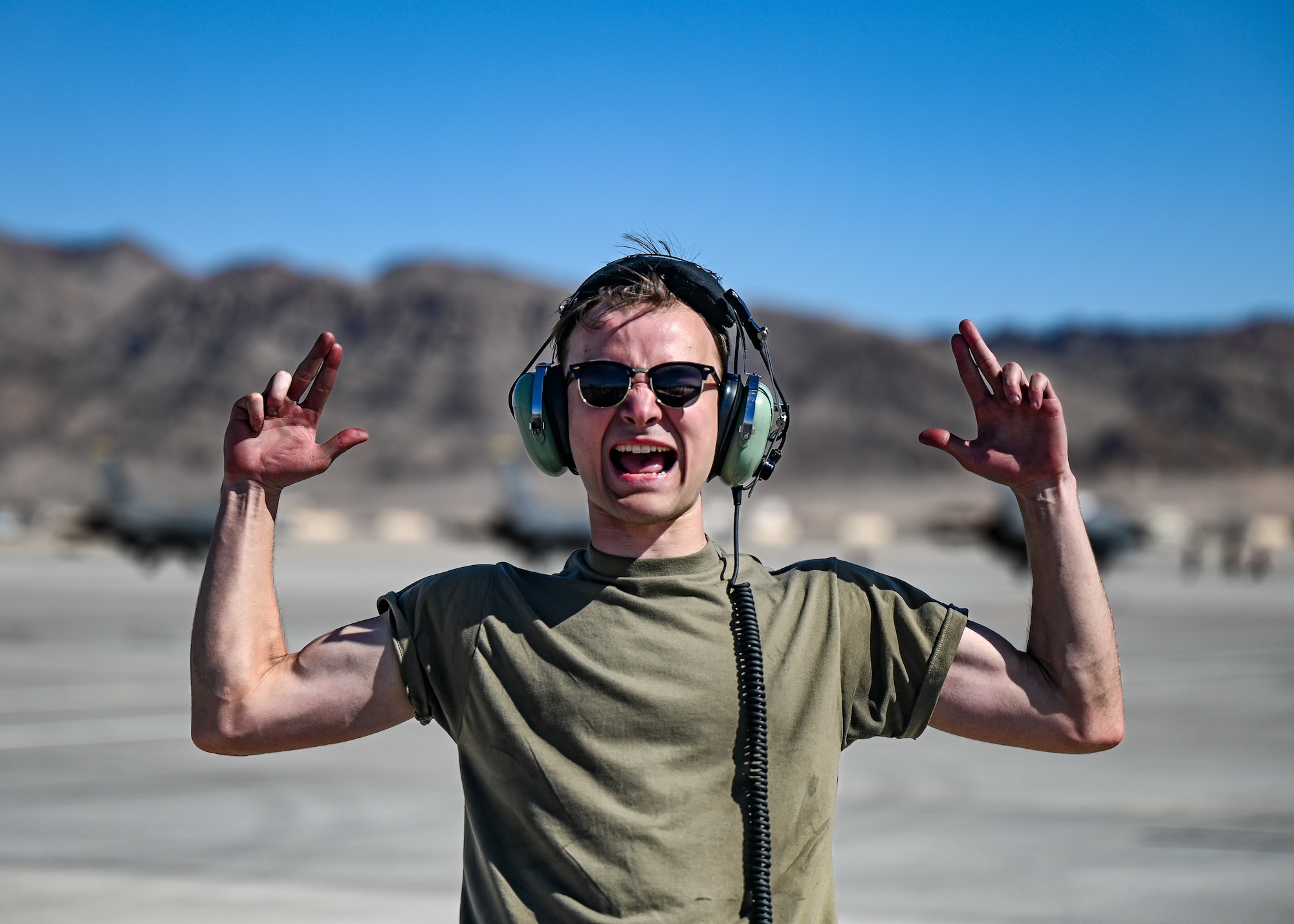 U.S. Air Force Senior Airman Kieran Smith, 55th Fighter Generation Squadron crew chief, expresses his excitement during the first day of exercise Red Flag-Nellis 23-2 at Nellis Air Force Base, Nevada, March 13, 2023. The 20th Maintenance Group is a vital component to the Wild Weasel mission and the Airmen involved in Red Flag 23-2 are critical to delivering combat airpower. (U.S. Air Force photo by Staff Sgt. Madeline Herzog)