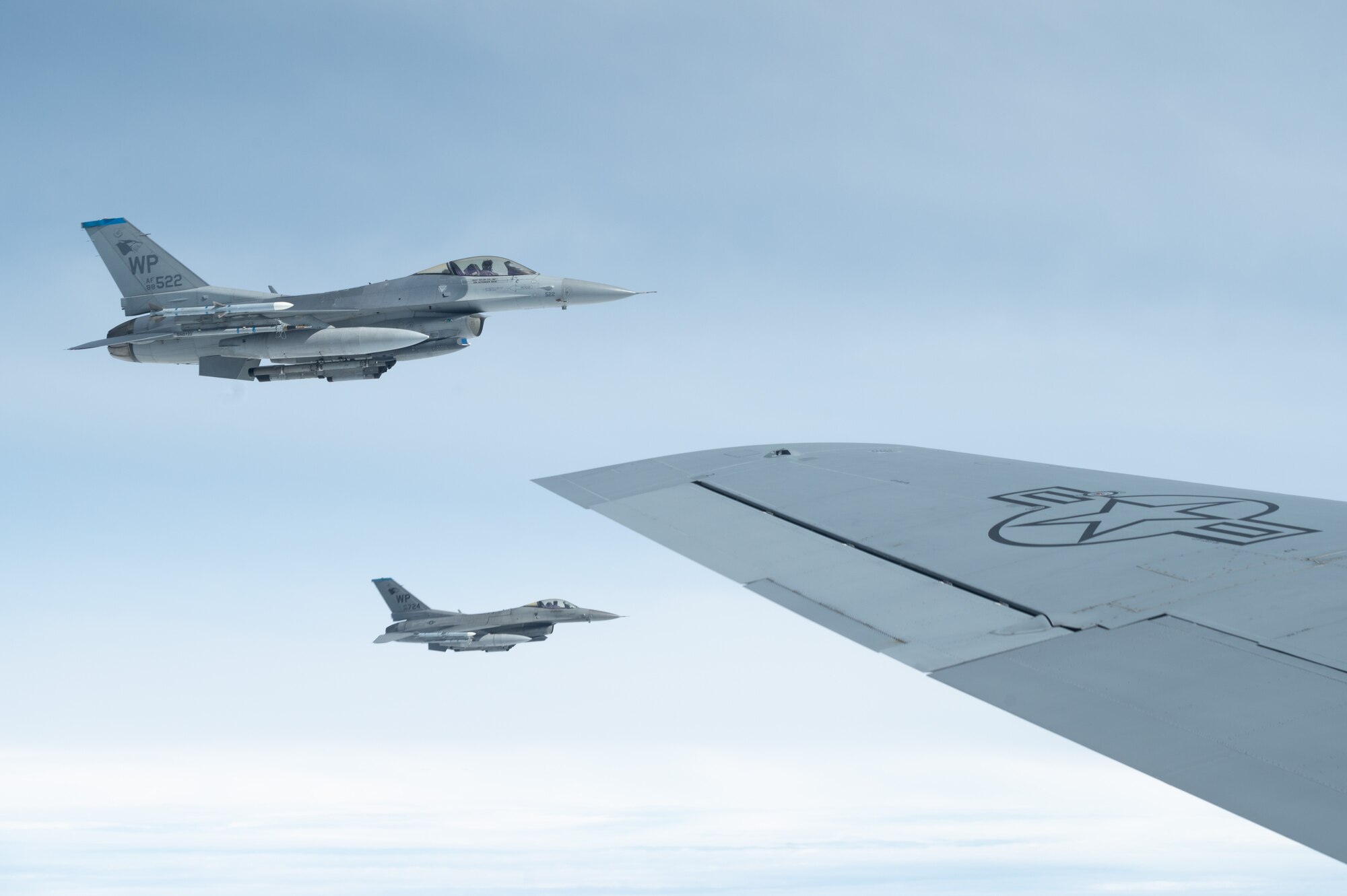 Two jets fly alongside another jet