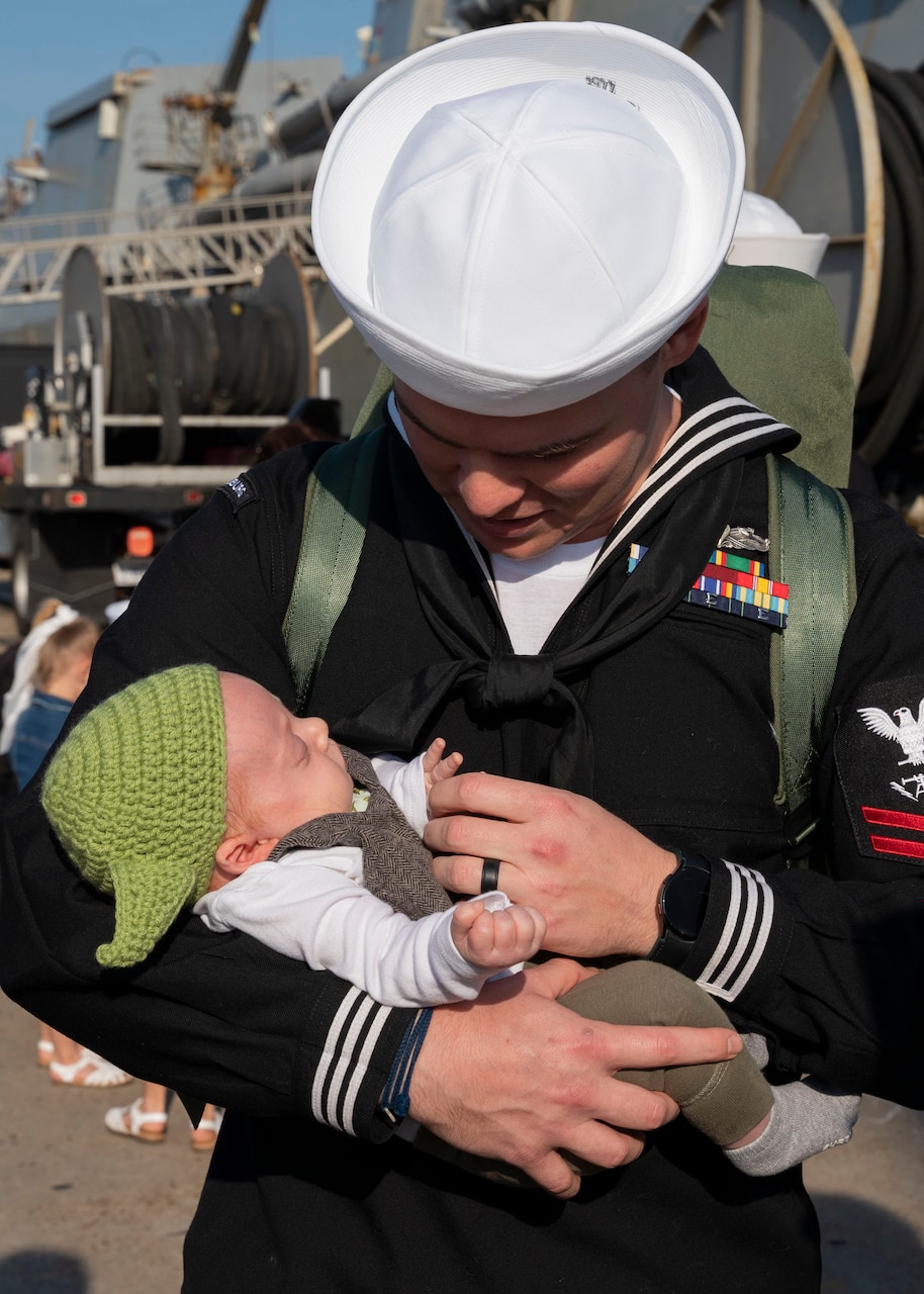 Fire Controlman (Aegis) 2nd Class Robert Heinke, assigned to the guided-missile cruiser USS Vicksburg (CG 69) and deployed with guided-missile destroyer USS Nitze (DDG 94), meets his daughter for the first time after Nitze returned to Naval Station Norfolk following a scheduled deployment April 5, 2023.