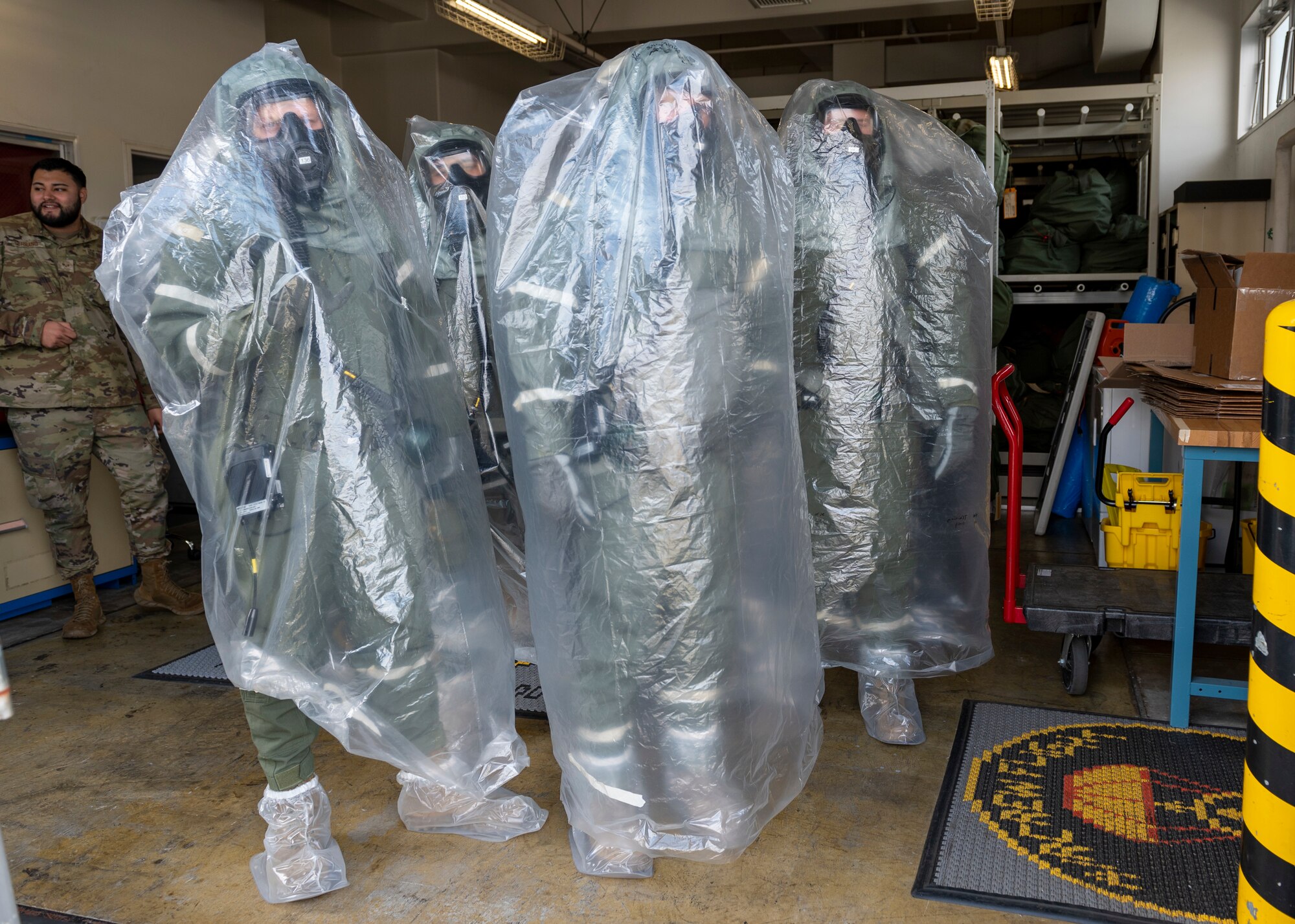 Four pilots stand in a loading bay covered in plastic bags