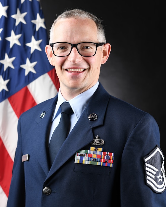Airman posed in front of a flag