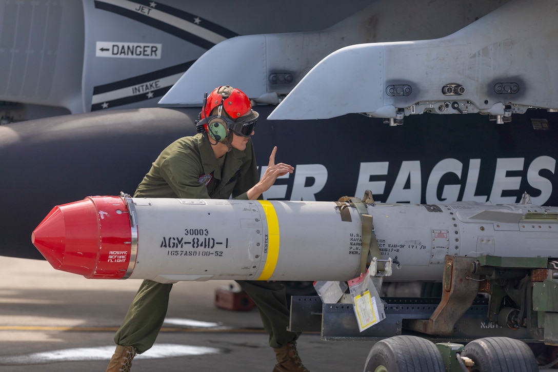 A Marine signals as he helps to load a missile.