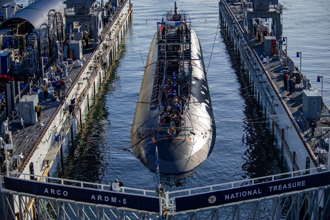 A submarine floats between two docks.