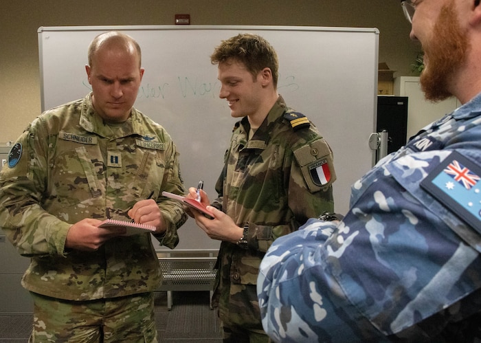 Schriever Wargame 2023 participants compare notes March 24, 2023, during the wargame held at Air University, Maxwell Air Force Base, Ala. The wargame brought together more than 350 military members from eight nations at the Air Force Wargaming Institute to take part in the two-week wargame, which ended March 31. SW 23 participants engaged in scenario-based planning exercises designed to improve strategic and operational decision-making to strengthen national and multinational priorities. (U.S Air Force photo by Airman Tyrique Barquet) (Group Caption)