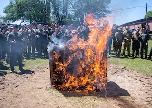 a crowd of people watch a burning piano during a ceremony