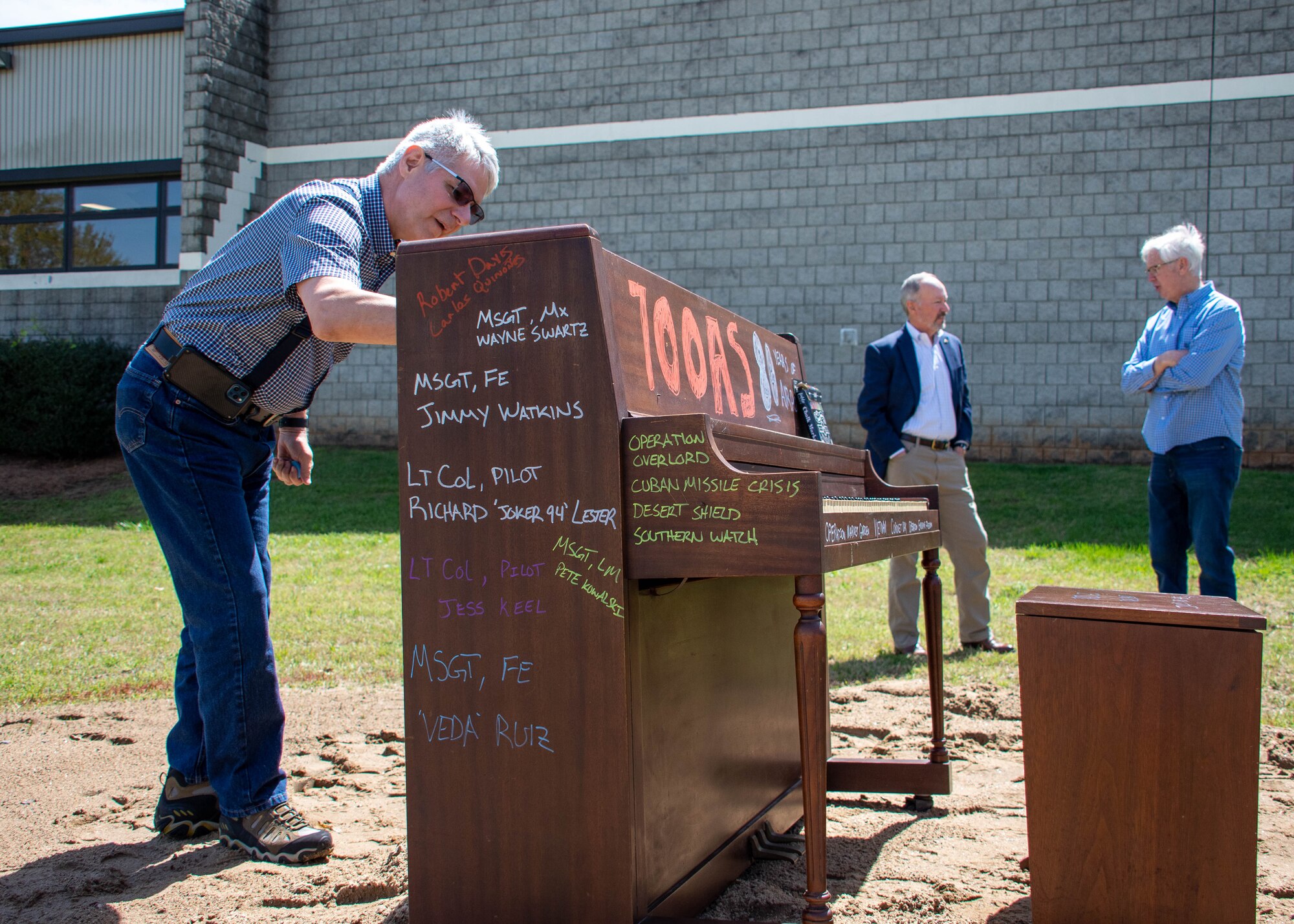 people sign a piano during a ceremony