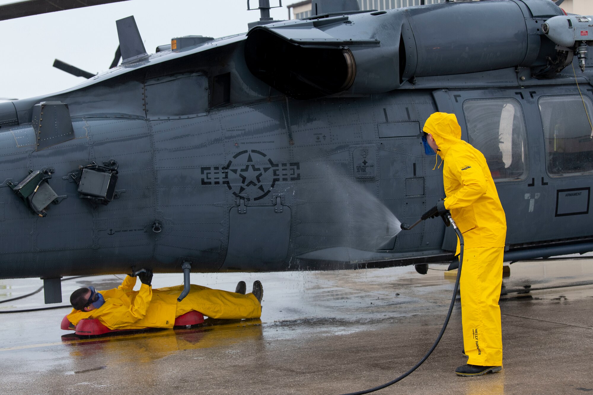 U.S. Air Force Chief Master Sgt. Chad Fry, 510th Fighter Generation Squadron senior enlisted leader, right, and Capt. Justin Berte, 56th Rescue Generation Squadron director of operations, left, wash an HH-60G Pave Hawk helicopter as part of an immersion tour
