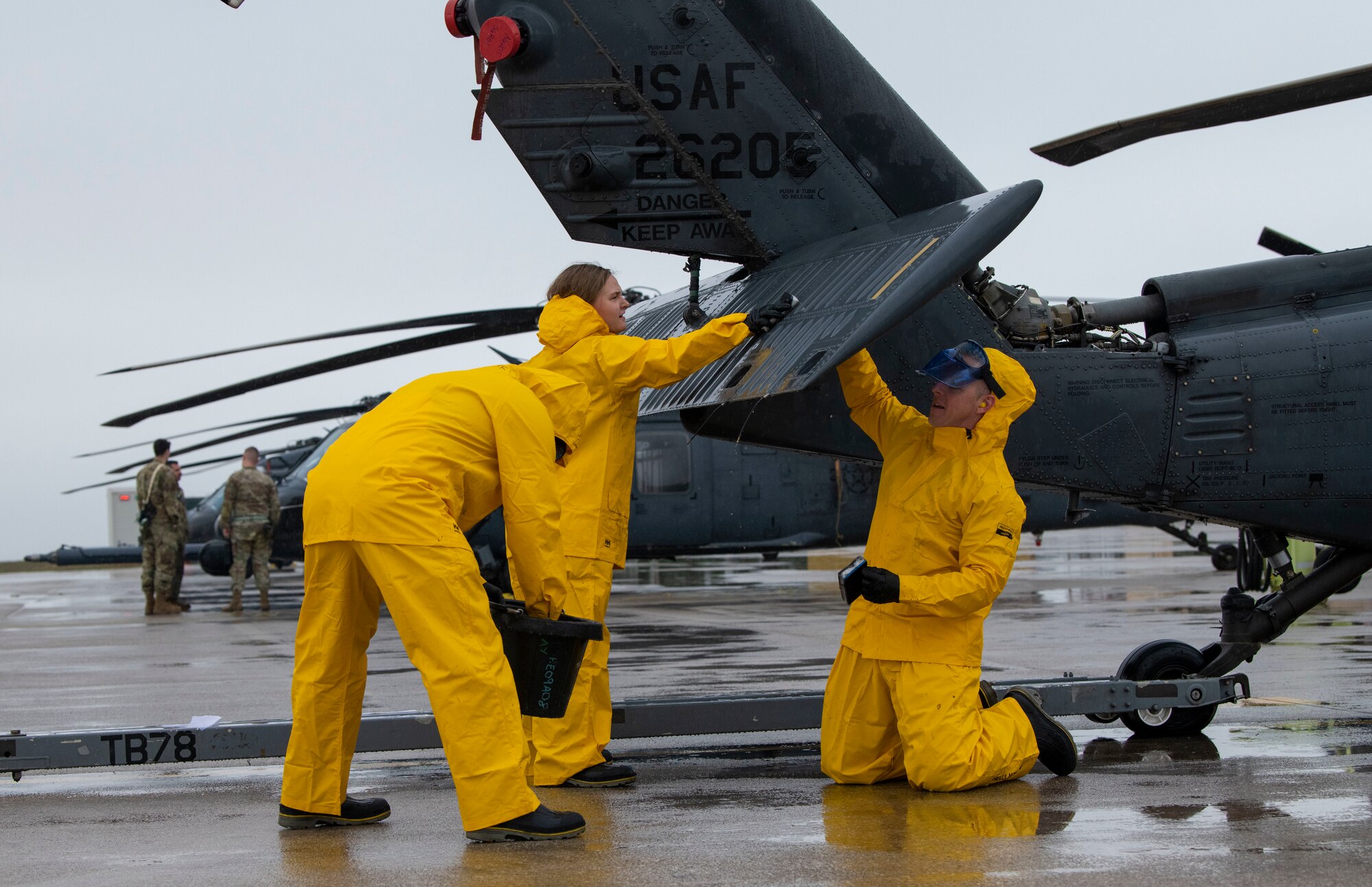 U.S. Air Force Chief Master Sgt. Chad Fry, 510th Fighter Generation Squadron senior enlisted leader, left, Col. Jason Mitchell, 31st Maintenance Group commander, middle-left Capt. Justin Berte, 56th Rescue Generation Squadron director of operations, middle, and 2nd Lt Constance Stormzand, 555th Fighter Generation Squadron sortie support flight commander, right, wash the tail of an HH-60G Pave Hawk helicopter as part of an immersion tour