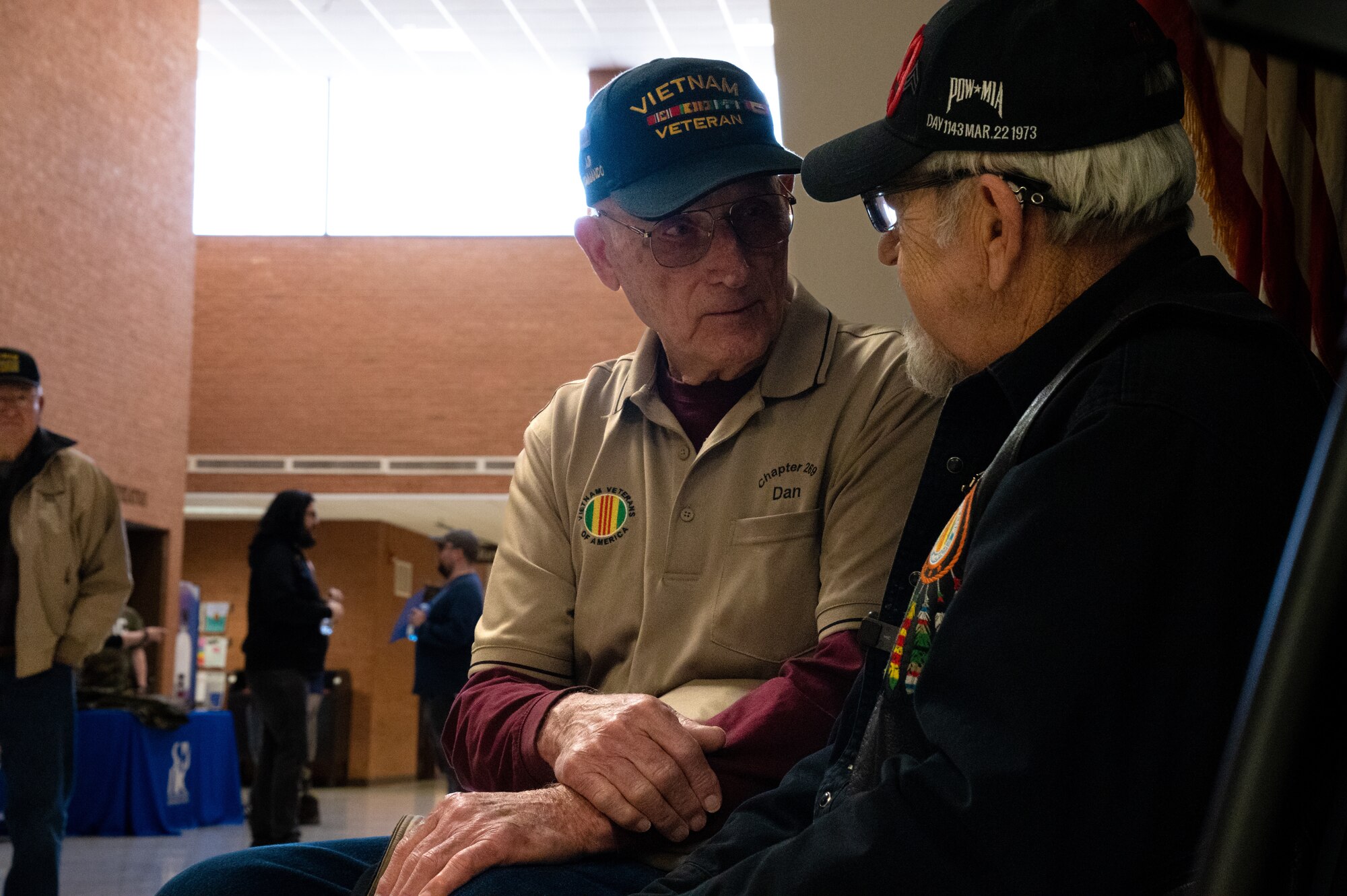 Two men sit and talk to each other.