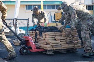 Members of U.S. Coast Guard Law Enforcement Detachment 406 push bales of illegal narcotics aboard USS Farragut (DDG 99) for a drug offload in Port Everglades, Florida, April 4, 2023.