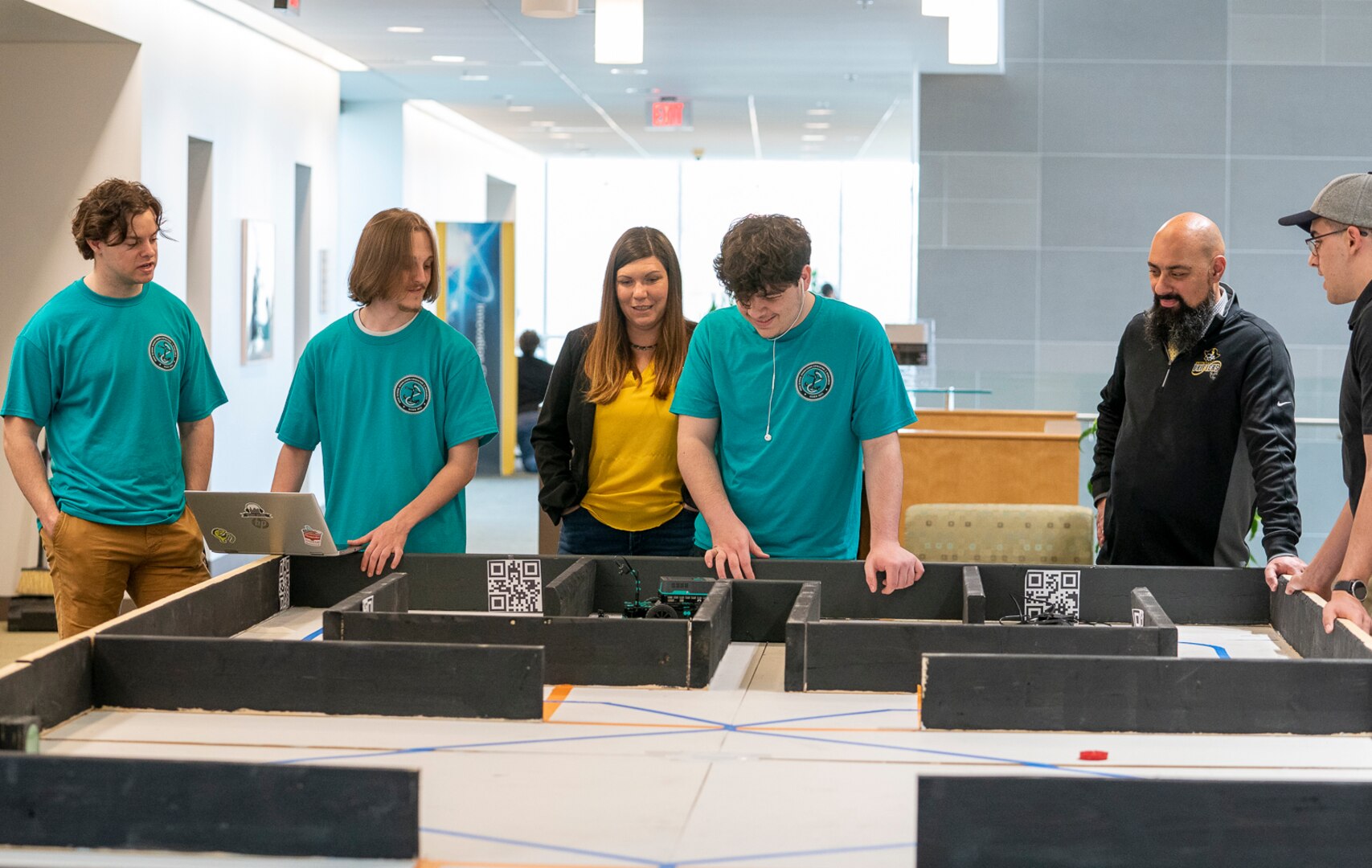 IMAGE: Colonial Beach Mayor Robin Schick visits the Colonial Beach High School robotics team as they run their robot through a practice course during the second day of the High School Innovation Challenge @ Dahlgren.