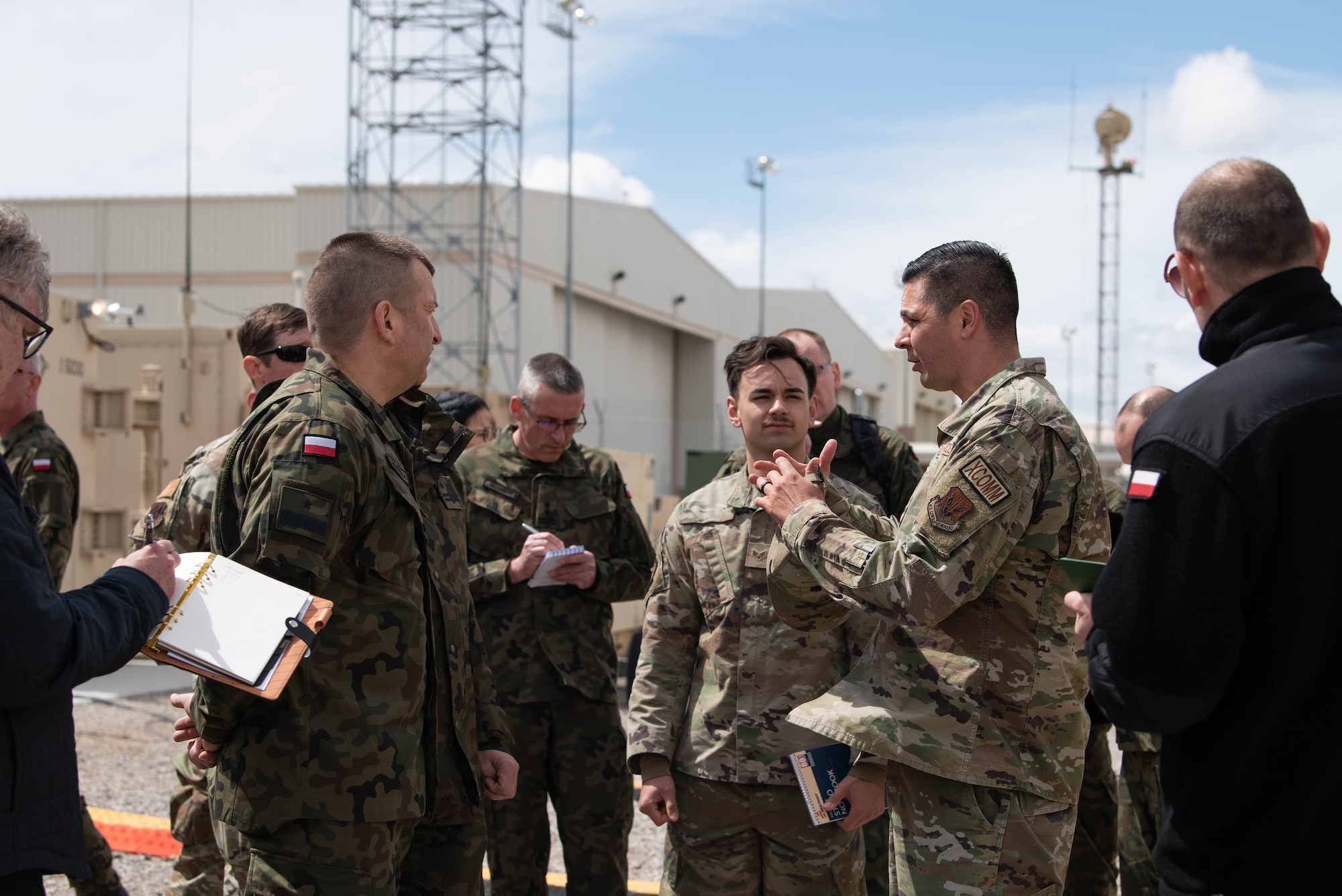 U.S Air Force Airmen and Polish delegation gather around and brief on RPA mission equipment.