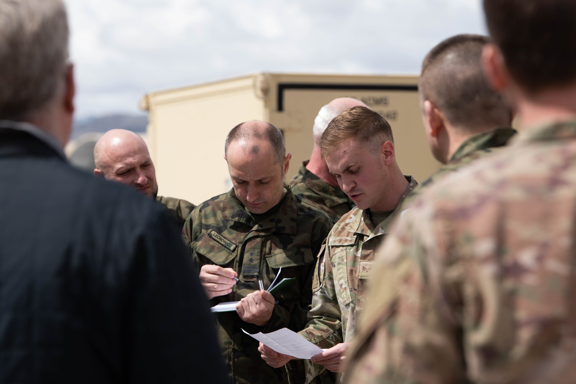 U.S Air Force Airmen and Polish delegation gather around and brief on RPA mission equipment.