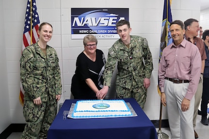IMAGE: Naval Surface Warfare Center Dahlgren Division Dam Neck Activity (NSWCDD DNA) hosts a cake cutting ceremony, April 5, celebrating 60 years since the command was first established. NSWCDD DNA was first commissioned on March 31, 1963, as the Fleet Computer Programming Center, Atlantic, and has since undergone various name changes over the last 50 years. Pictured (left to right): Cmdr. Christina Carino, commanding officer NSWCDD DNA; Mary Kay Anderson, integrated training systems division head; Information Systems Technician 2nd Class Joseph Parker; Dave Richardson, NSWCDD DNA senior civilian and department head.