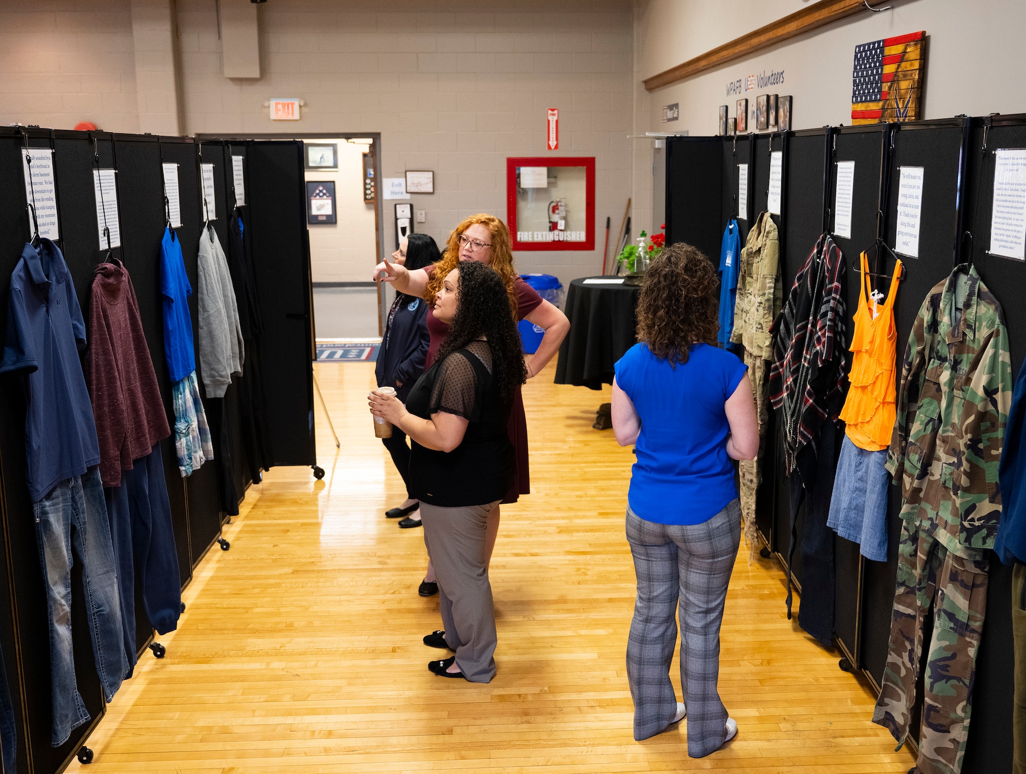 A group of women stand looking at a display of clothing and accounts of sexual assaults.