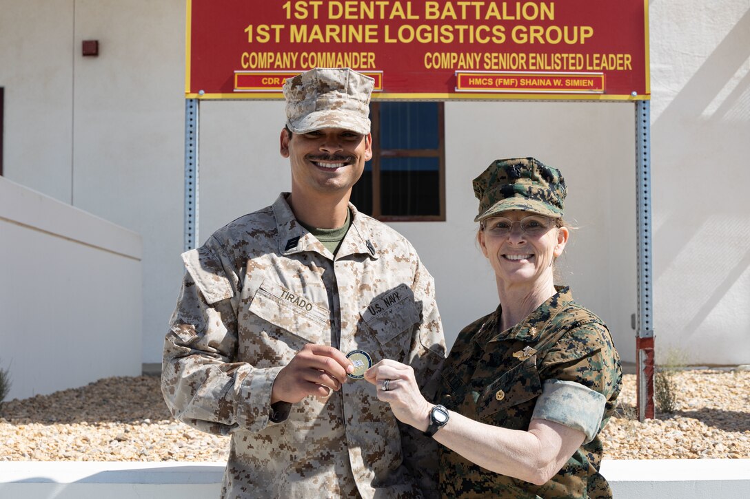 U.S. Navy Rear Adm. Pamela Miller, medical officer of the Marine Corps, presents a challenge coin to a Sailor assigned to 23rd Dental Company