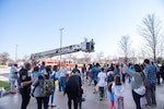 A person dressed as the Easter Bunny waves from the bucket of a red ladder truck.