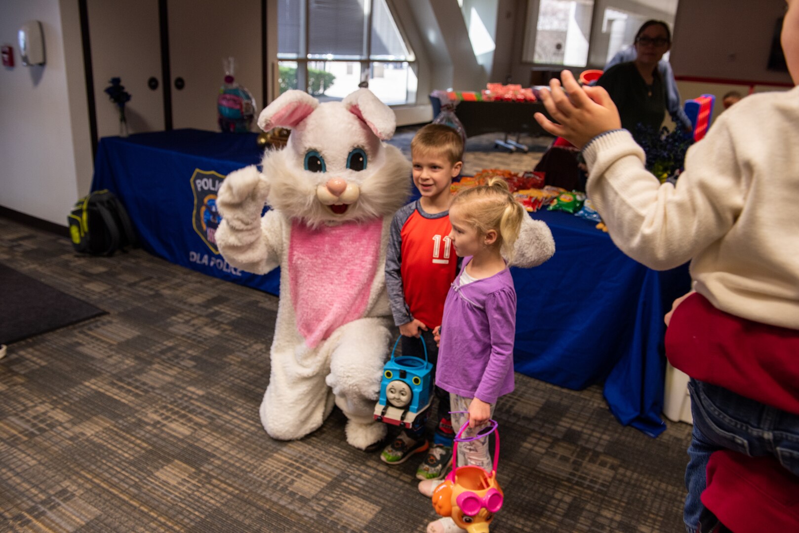 Children pose with a person dressed as the Easter Bunny who is kneeling to get down to their vantage point for a photo.