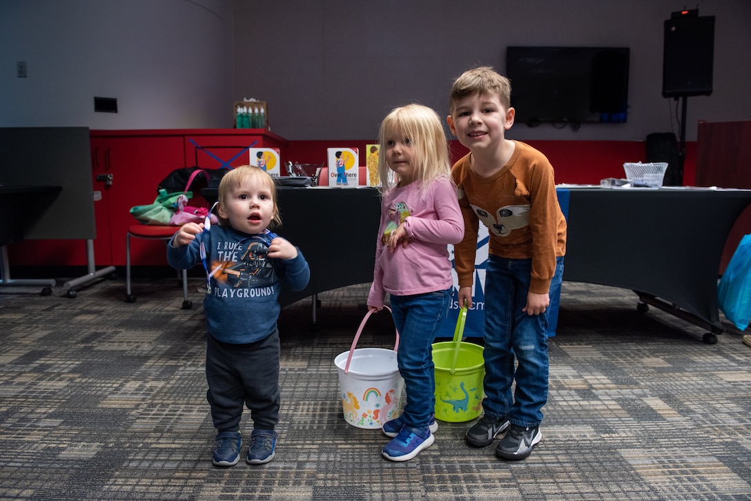 Three children smile at the camera with one child without a basket and two children with baskets. They are waiting for the hunt to begin.