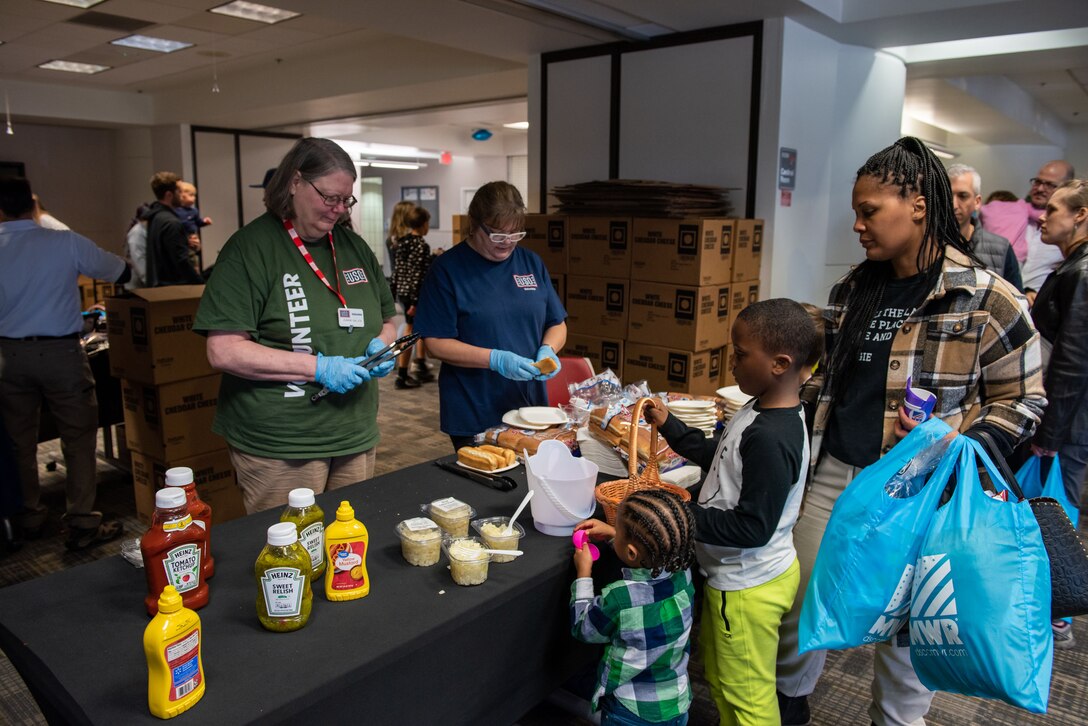 Children line up to get hot dogs at the hot dog table.