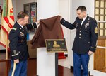 Col. Christopher L. Tomlinson, left, commander of U.S. Army Garrison Japan, and Command Sgt. Maj. David A. Rio, the garrison's senior enlisted leader, unveil a plaque during a ceremony to rename the garrison's headquarters building at Camp Zama, Japan, April 5, 2023. The building, commonly referred to as Building 102 or the Garrison building, is now named the Col. David B. Hannum Jr. Garrison Headquarters Building in honor of the former garrison commander.