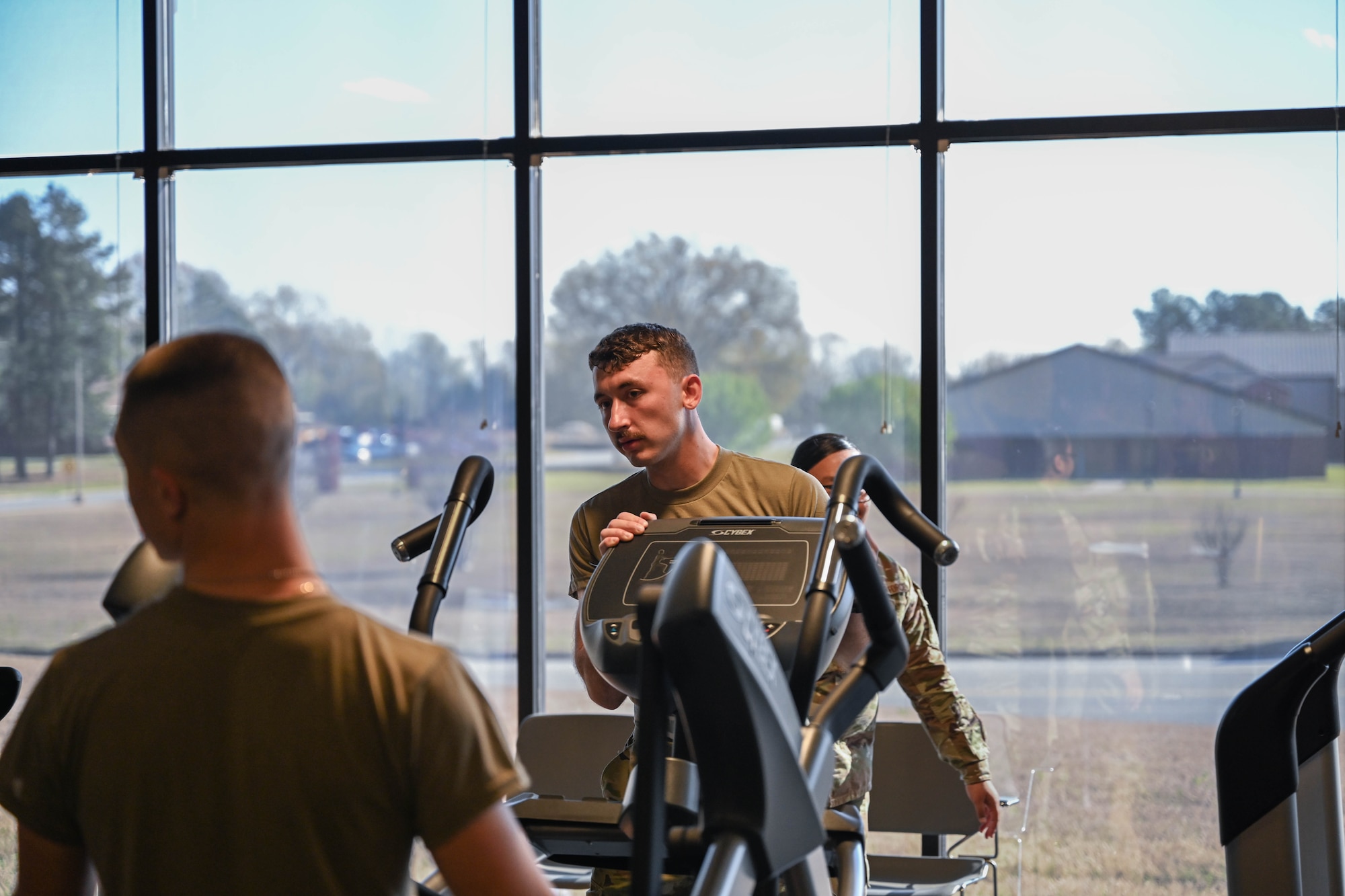 Men in uniform carry exercise equipment.