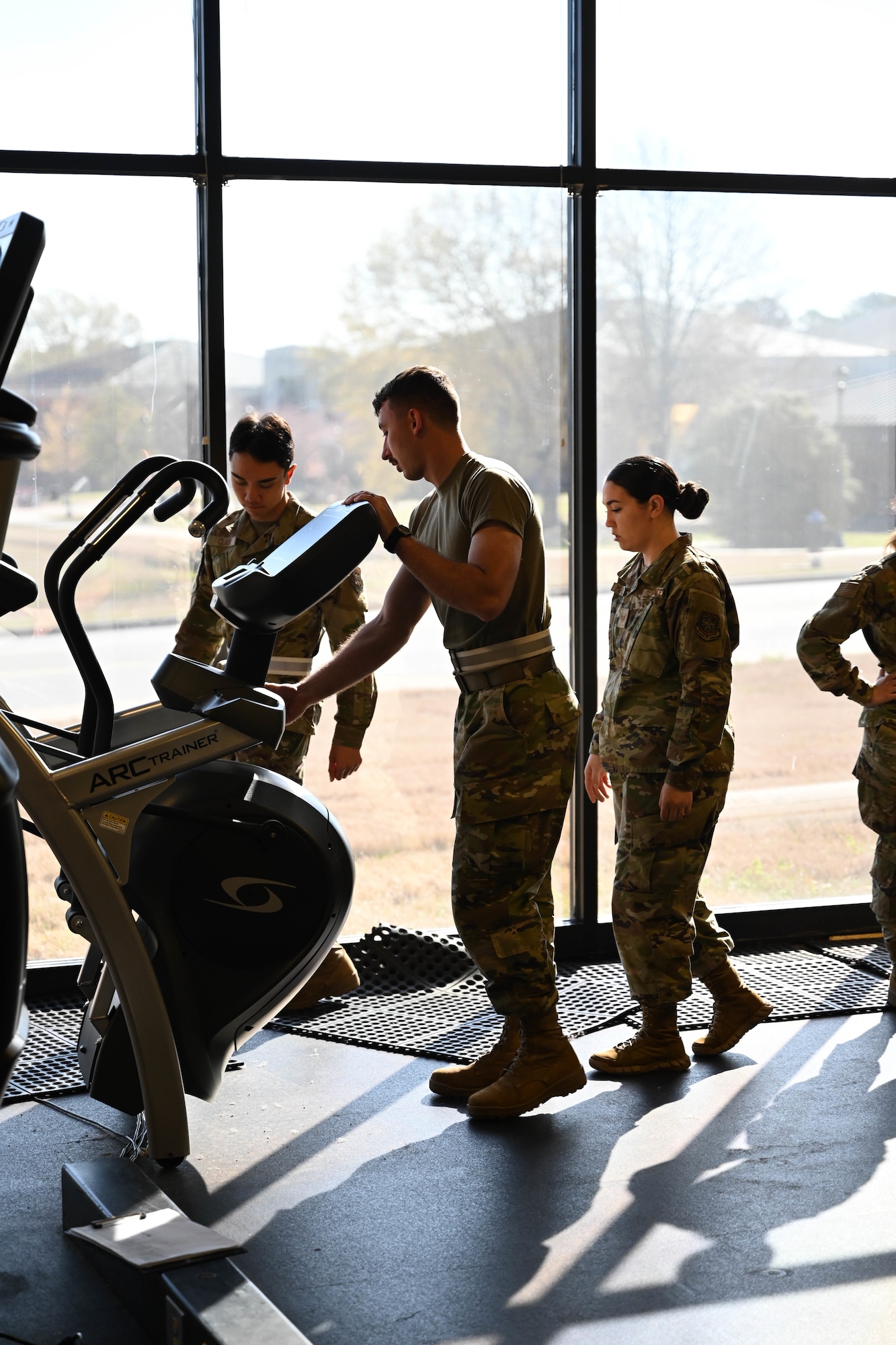 People in uniform move exercise equipment.