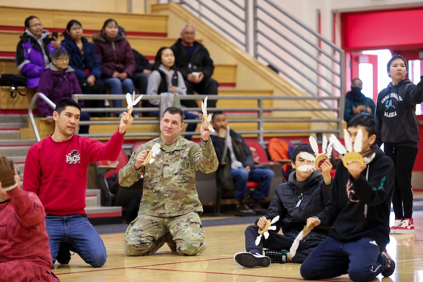Alaska Army National Guard Staff Sgt. Eddie Jones, a Bethel-based recruiter, joins Andreafski High School students as they perform a traditional Yup’ik dance in St. Mary’s, Alaska, March 31, 2023. The Association of Village Council Presidents recently partnered with the Alaska National Guard to provide recruiting information and resources through their Tribal Job Centers. The initiative kicked off in St. Mary’s with presentations from AVCP and AKNG, where representatives interacted with students, parents, teachers, and community members. AVCP provides community development, education, social services, culturally relevant programs, and advocacy for the people and 56 tribes of Western Alaska.