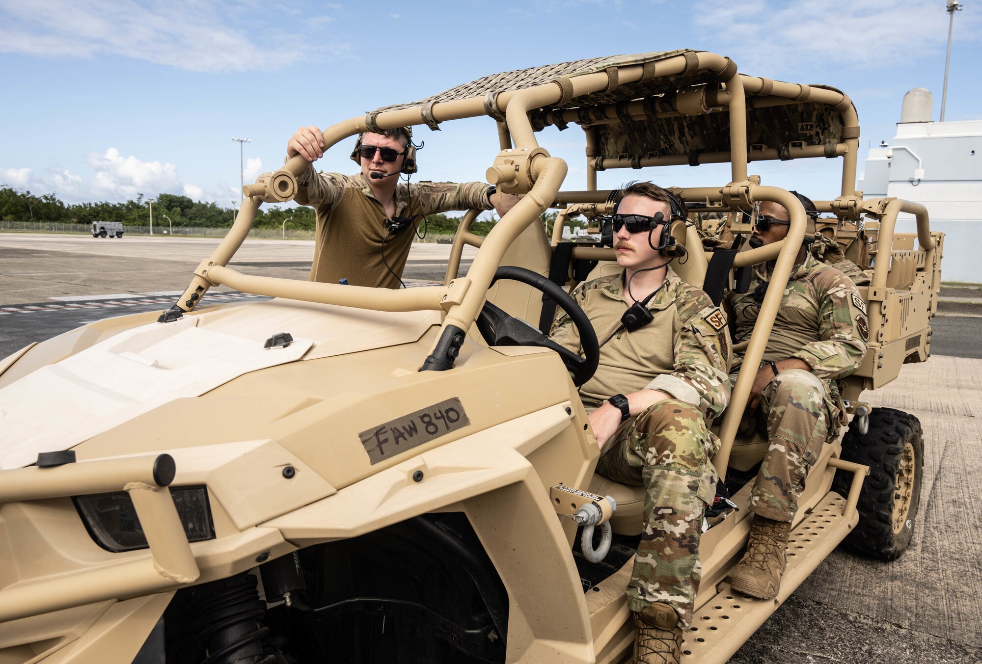 Security Forces Airmen sit in open-air vehicle on the flight line.
