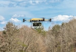 A drone flies above trees.