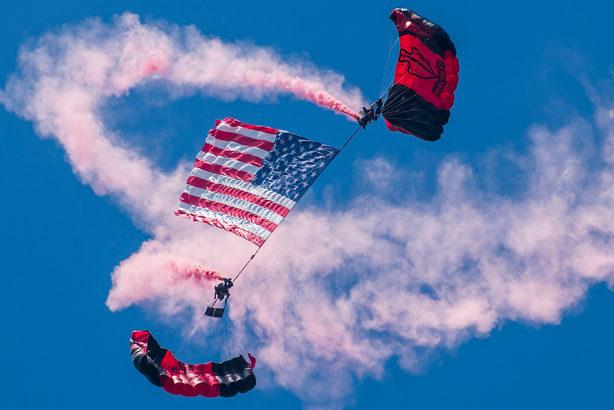 People with parachutes holding flag in the sky