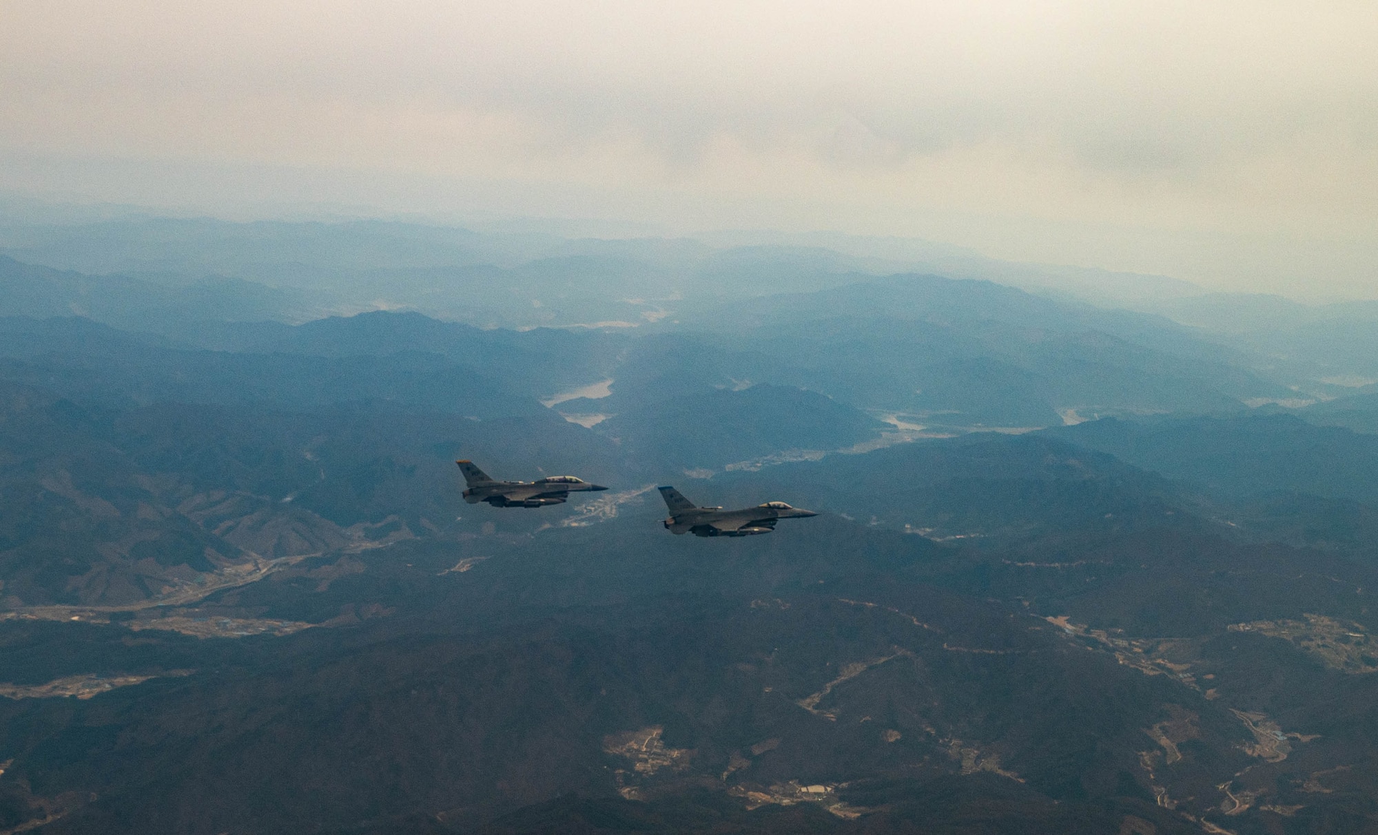 Two F-16 Fighting Falcons assigned to the 8th Fighter Wing, Kunsan Air Base, Republic of Korea, fly over the Korean Peninsula, April 4, 2023. The F-16 Fighting Falcon is a highly maneuverable, multi-role fighter aircraft that provides a relatively low-cost, high-performance weapon system for the United States and allied nations. The Air Force Life Cycle Management Center has provided the F-16 fleet various modifications and upgrades since entering the Air Force inventory in 1979. The Post Block Integration Team (PoBIT) project is the most recent large-scale upgrade to the F-16, encompassing 22 combined modifications that increase survivability and accuracy of the weapon system. (U.S. Air Force photo by Captain Kaylin P. Hankerson)