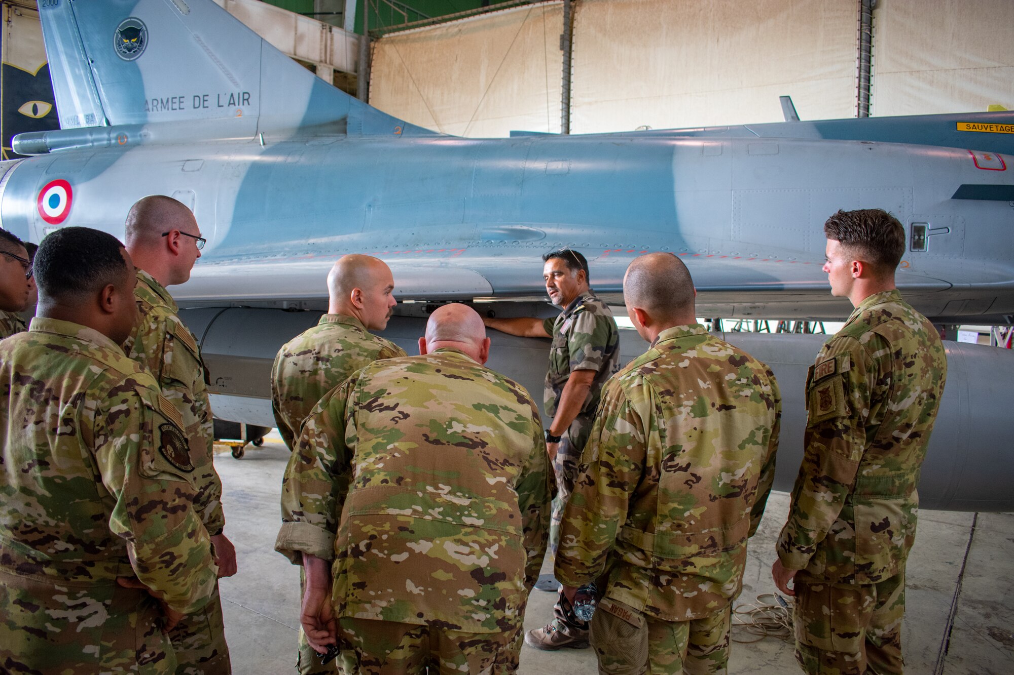 Commandant (Major) Eric from the 03/011 CORSE French fighter squadron shows 776th Expeditionary Air Base Squadron firefighters emergency procedures on the French Mirage 2000 at Base aerienne 188 “Colonel Massart”, Djibouti, Feb. 15, 2023. These joint training opportunities increase capabilities for both American and French Forces operating in east Africa. (U.S. Air Force photo by Tech. Sgt. Jordan LaPoint)