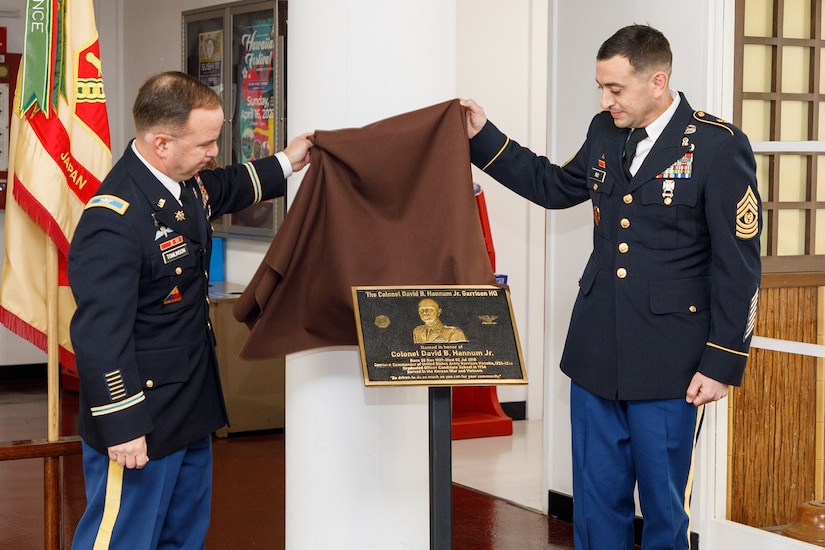 Two soldiers unveil a plaque.