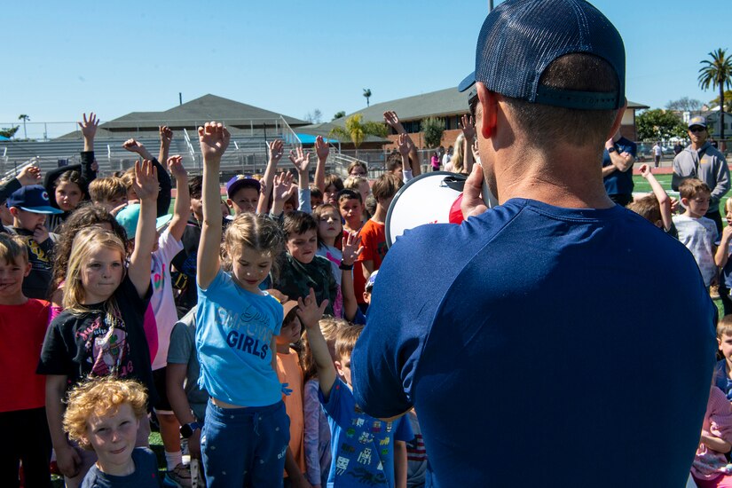 Students raise their hands during a Navy presentation.
