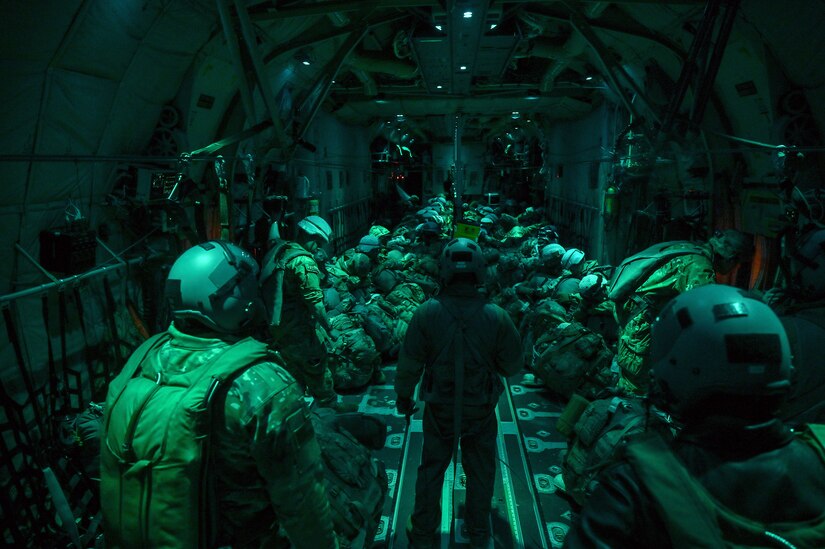 Airmen line up inside a military aircraft at night.