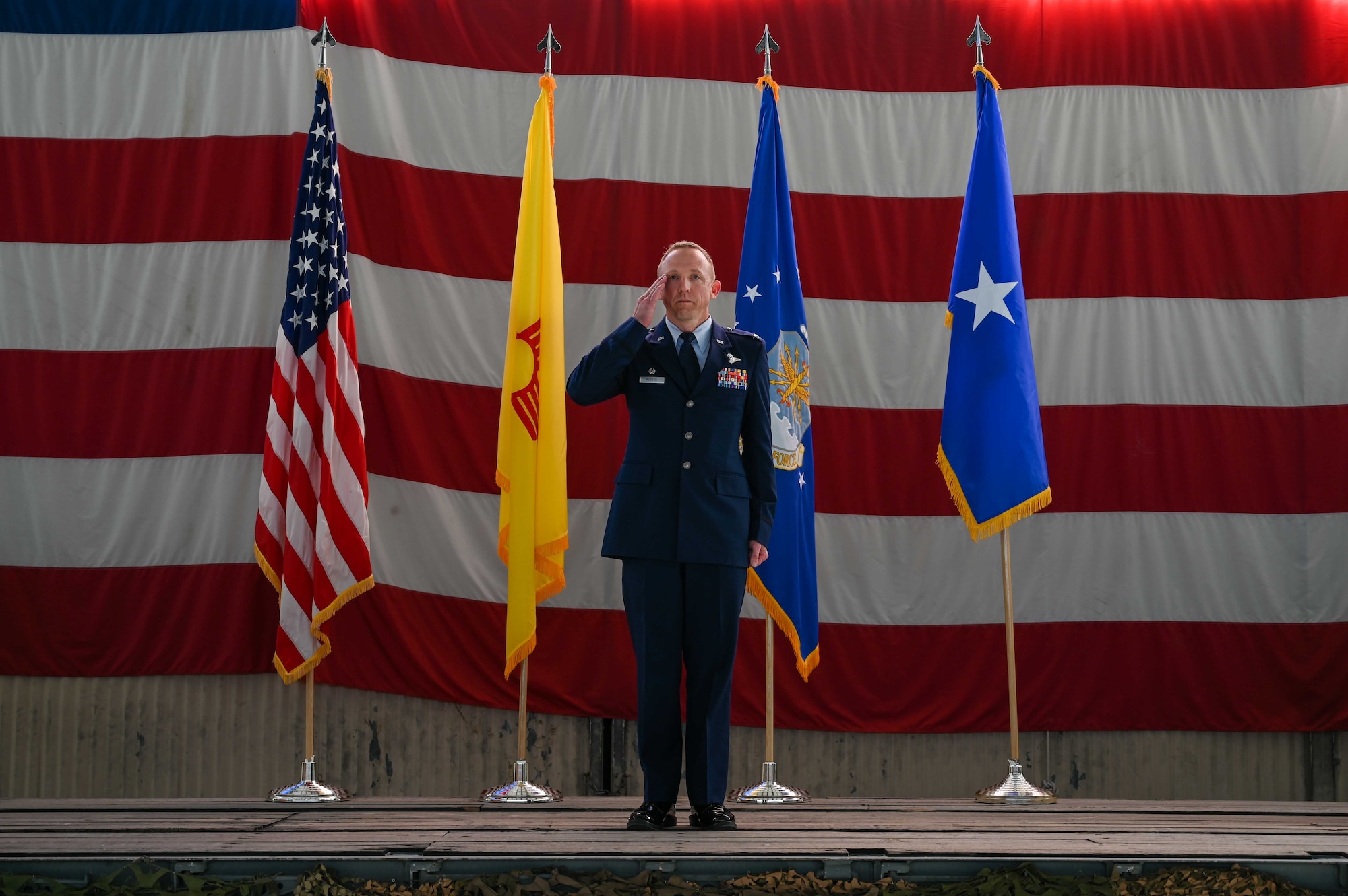 A man in a military uniform salutes from a stage.