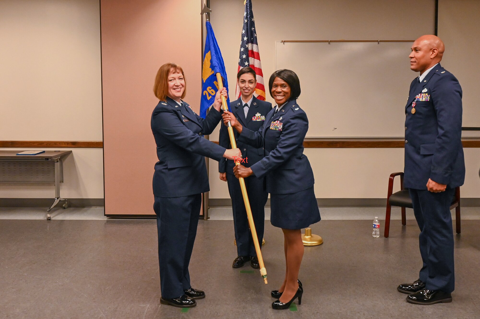 Col. Jeane Bisesi, center left, 433rd Mission Support Group commander, passes the 26th Aerial Port Squadron guidon to Lt. Col. TeAnglia Moore, center right, signaling her assumption of command on April 1, 2023.