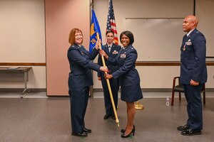 Col. Jeane Bisesi, center left, 433rd Mission Support Group commander, passes the 26th Aerial Port Squadron guidon to Lt. Col. TeAnglia Moore, center right, signaling her assumption of command on April 1, 2023.
