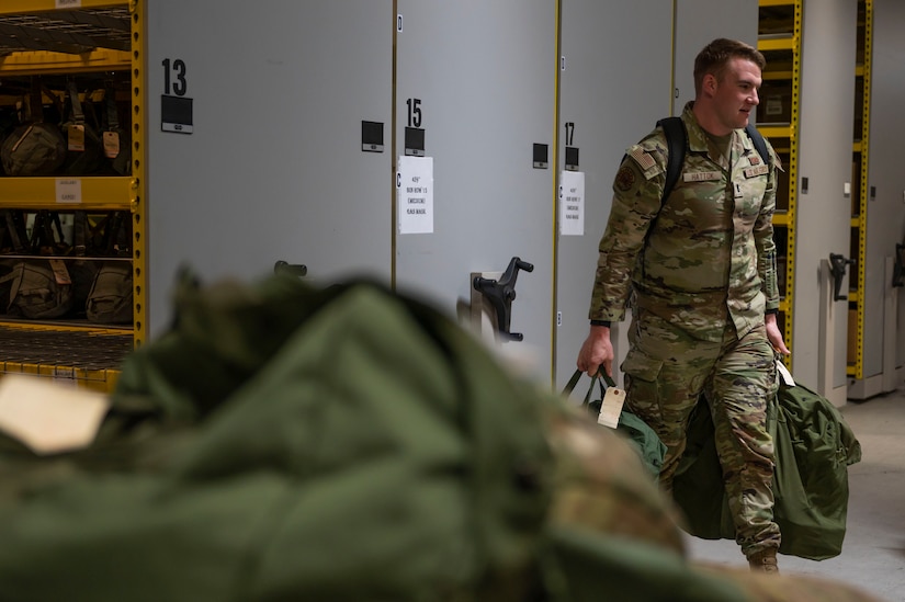 U.S. Air Force 1st Lt. Scott Hattok, 11th Civil Engineer Squadron project management chief, carries his individual protective equipment during a Personnel Deployment Function on March 30, 2023, at Joint Base Andrews, Md. Service members are required to complete a PDF to ensure they are mentally and physically prepared for their upcoming deployment. (U.S. Air Force photo by Jason Treffry)