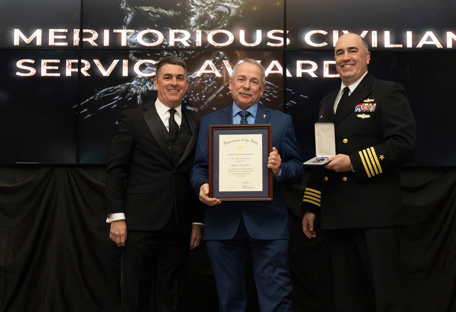 IMAGE: Naval Surface Warfare Center Dahlgren Division (NSWCDD) Technical Director Dale Sisson Jr., SES, and Commanding Officer Capt. Philip Mlynarski presented James McConkie with the Navy Meritorious Civilian Service Award during the NSWCDD Annual Honorary Awards ceremony at the Fredericksburg Expo Center March 10.