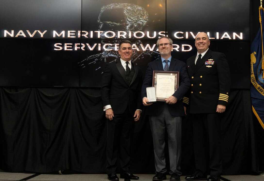 IMAGE: Naval Surface Warfare Center Dahlgren Division (NSWCDD) Technical Director Dale Sisson Jr., SES, and Commanding Officer Capt. Philip Mlynarski presented Thomas Moore with the Navy Meritorious Civilian Service Award during the NSWCDD Annual Honorary Awards ceremony at the Fredericksburg Expo & Conference Center March 10.