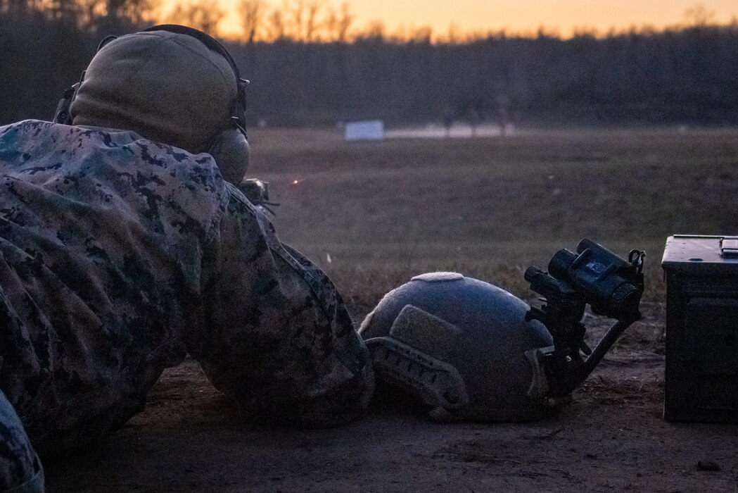 A Marine laying on the ground to aim his gun at a target.