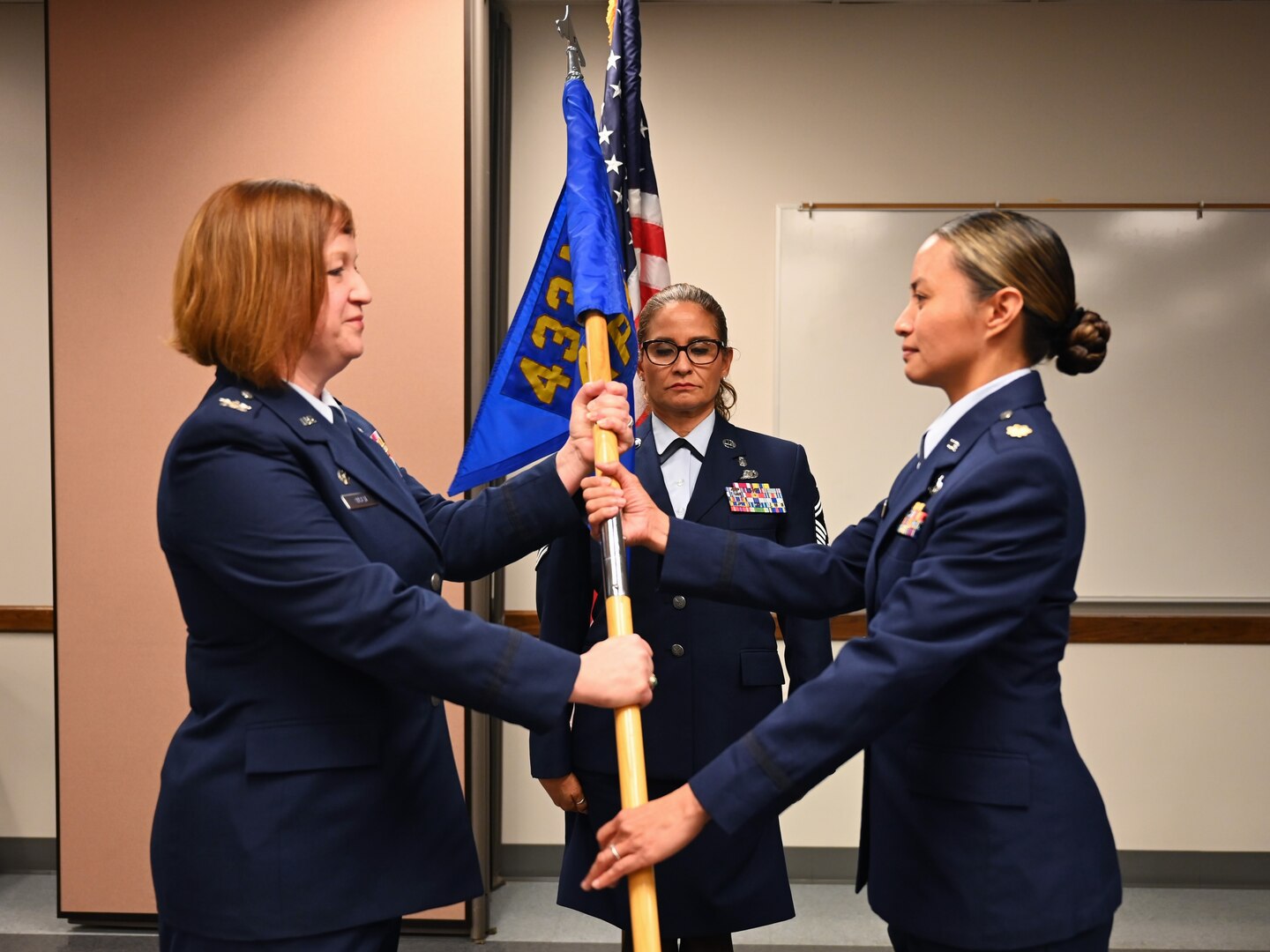 Col. Jeanne Bisesi, left, 433rd Mission Support Group commander, passes the 74th Aerial Port Squadron guidon to Maj. Valerie A. Mafnas, right, signaling her assumption of command on April 1, 2023.