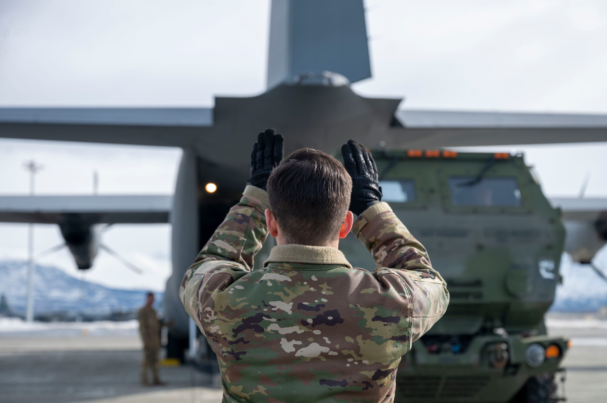 A loadmaster directs a HIMARS into a C-130J Super Hercules