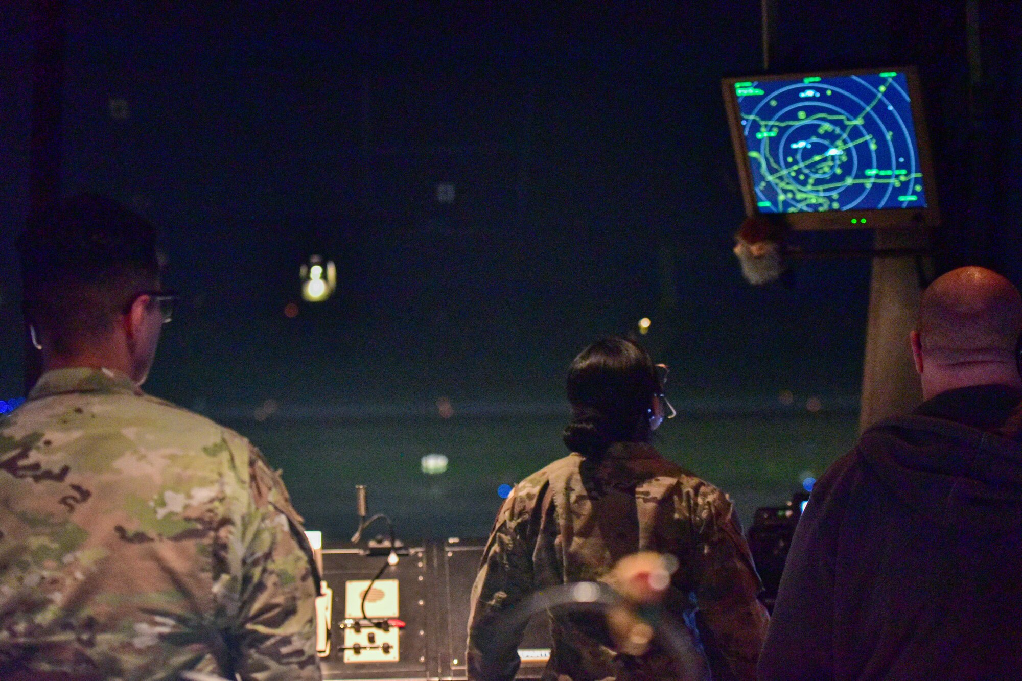 People in uniform look at a tv screen.