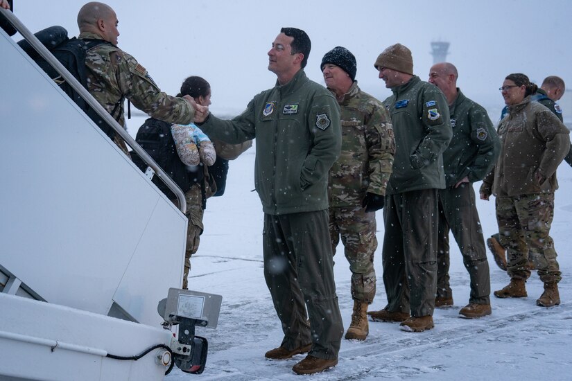A row of 3rd Wing officers fist bump Airmen as they leave their plane