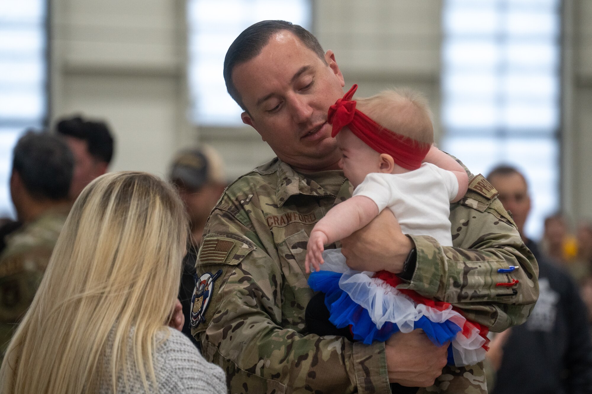 A U.S. Air Force Airman holds his baby daughter with his wife next to him